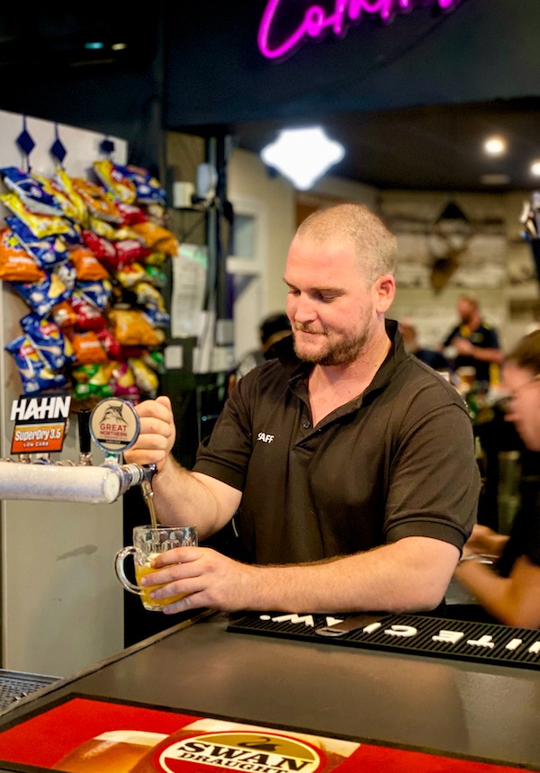 A staff member pouring a pint of beer for a customer.