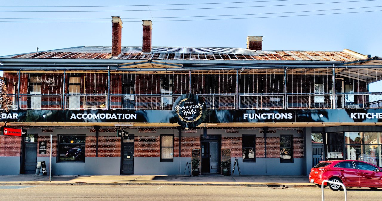 The Commercial Hotel Merredin, as viewed from Barrack Street during the afternoon. It is a characterful old brick building with two floors and a corrugated iron roof.